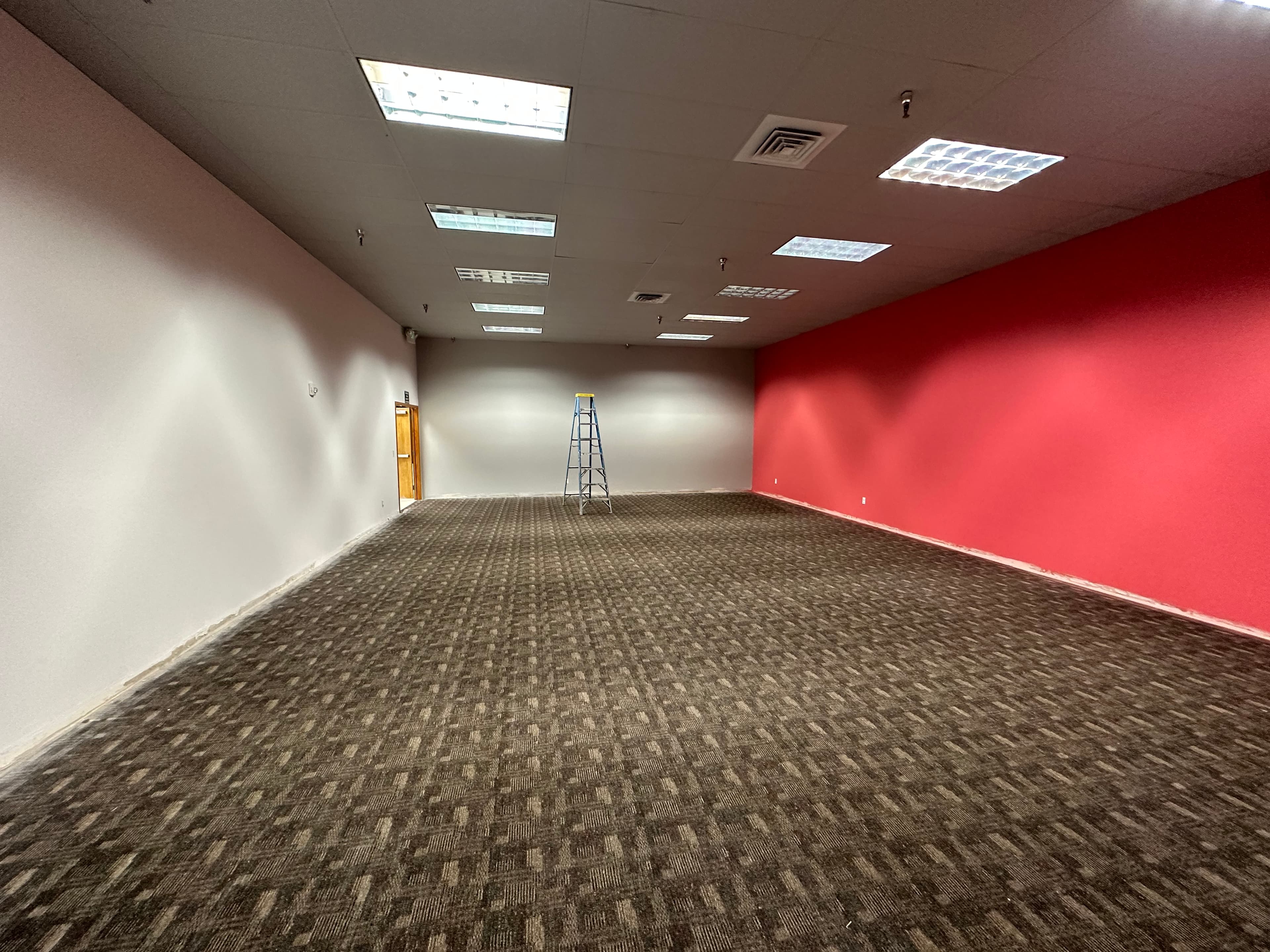 Empty Spokane, WA retail drywall space with red accent wall after commercial painting