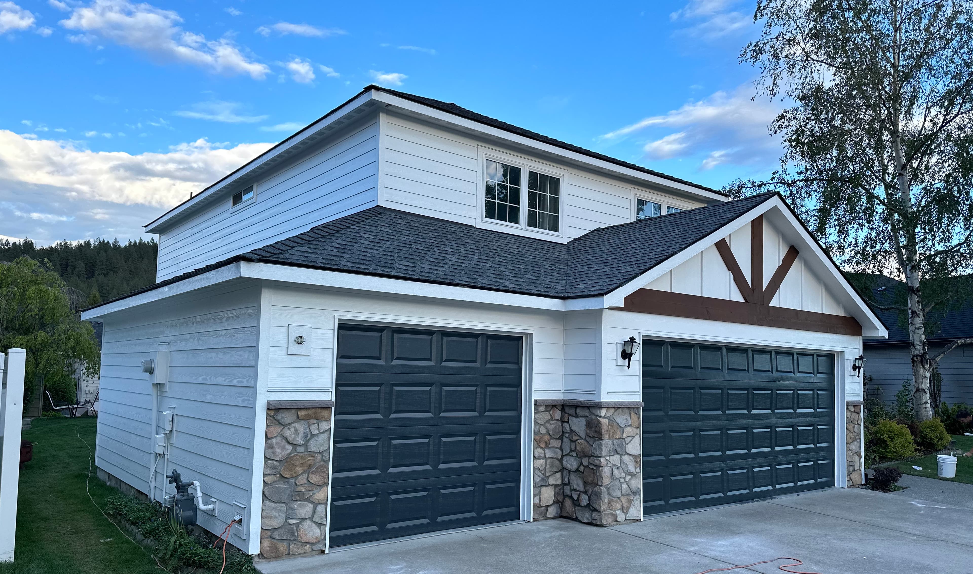 White Spokane, WA garage siding exterior repaint with dark doors and stone accents