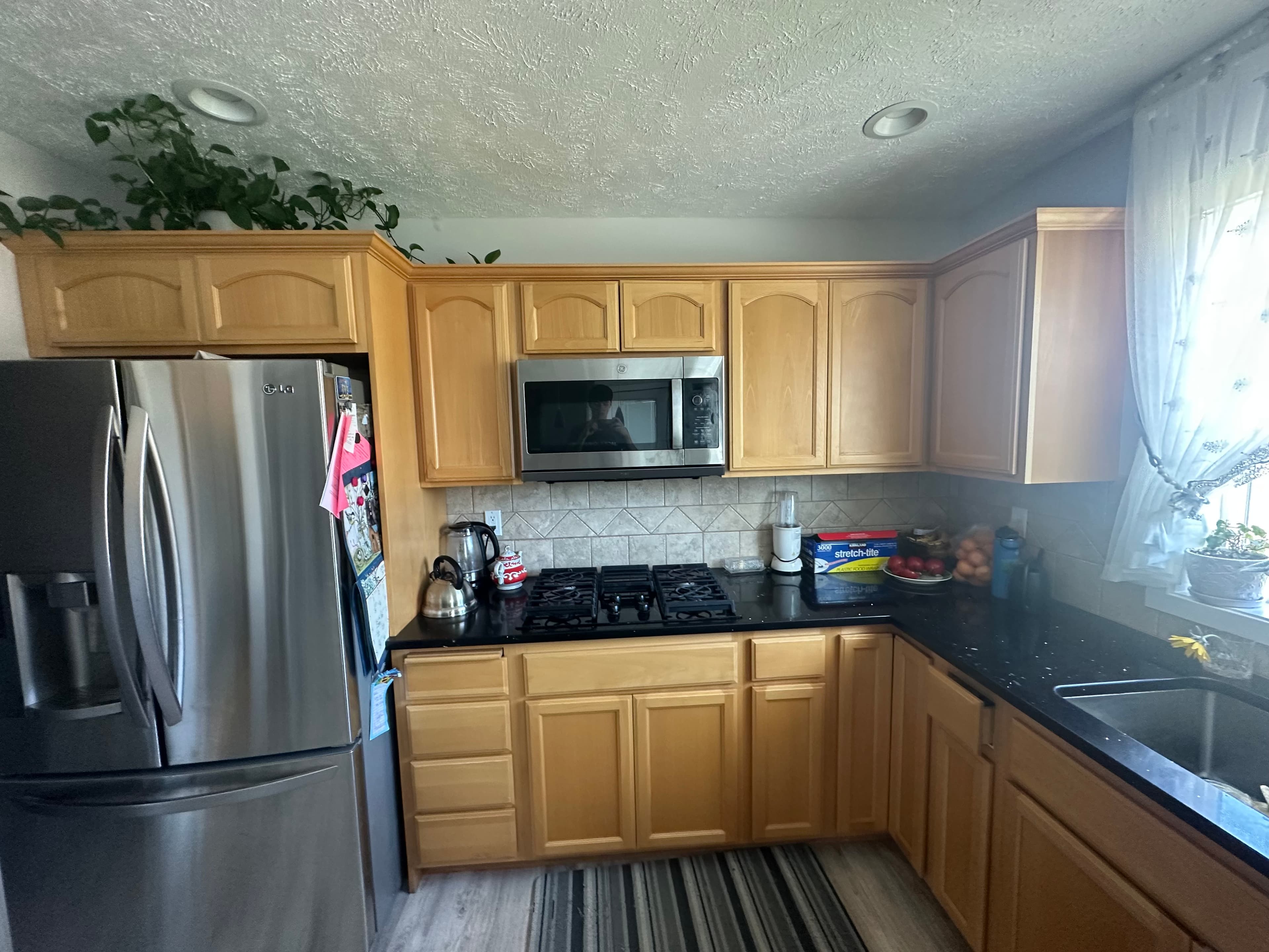 Oak cabinet refinishing in a Spokane, WA kitchen with dark countertops